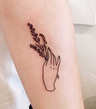 A foto da tatuagem de mão com flores em estilo handpoke no antebraço da menina