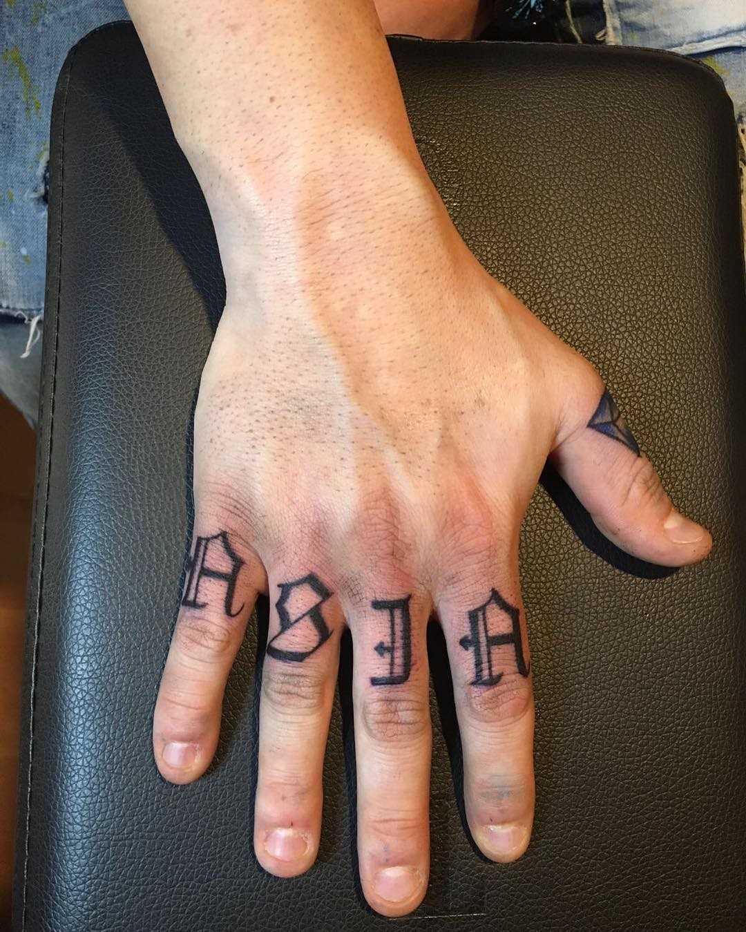 A foto da tatuagem de texto em estilo gótico em seus dedos do cara