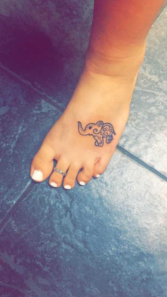 A foto da tatuagem de um elefante em estilo indiano, na planta do pé da menina