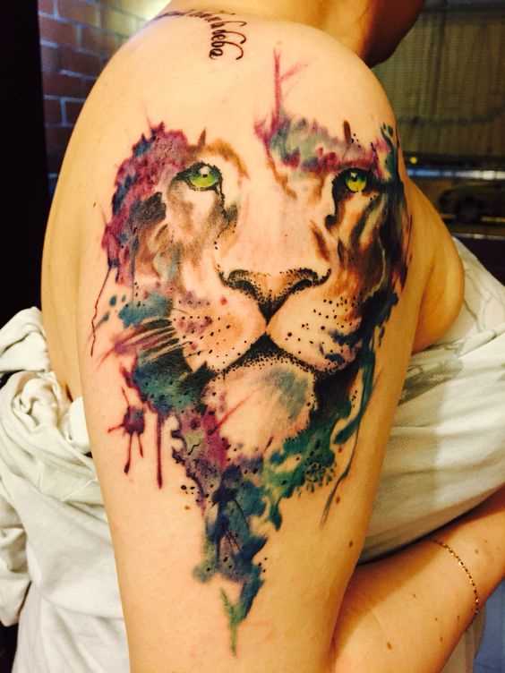 A foto da tatuagem de um leão em um estilo de aquarela no ombro da menina