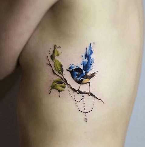 A foto da tatuagem de um pássaro no estilo aquarela sobre as costelas menina