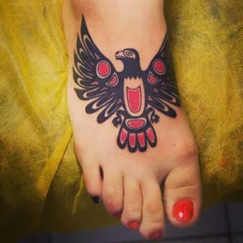 A foto da tatuagem de um pássaro no estilo haida na planta do pé da menina