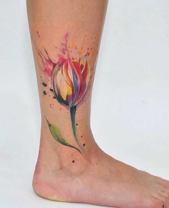 A foto da tatuagem de uma tulipa no estilo aquarela sobre a perna da menina