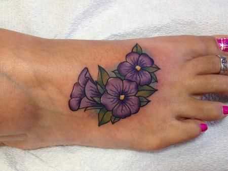 A foto da tatuagem de violetas na planta do pé da menina