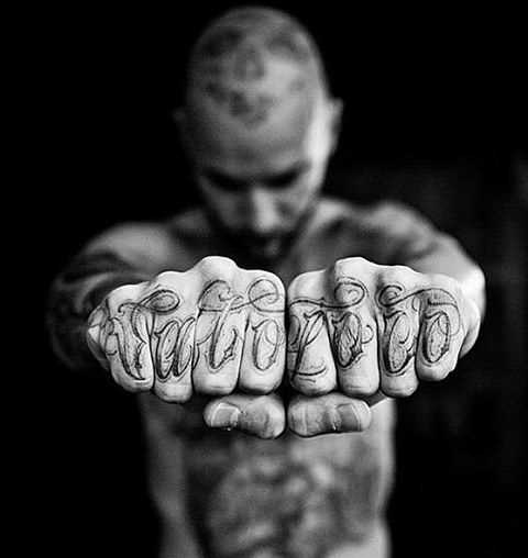 A inscrição dos dedos de um cara no estilo chicano - tatuagem