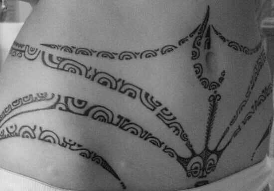 A tatuagem de padrões em estilo tribal na barriga da menina