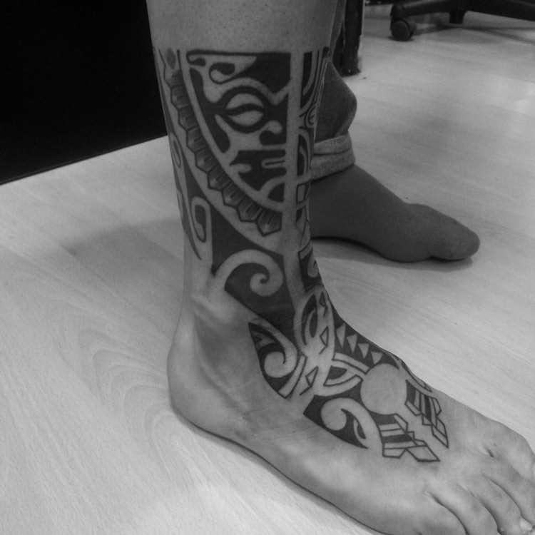 A tatuagem de padrões em estilo tribal na planta do pé de um cara - maiianskie padrões