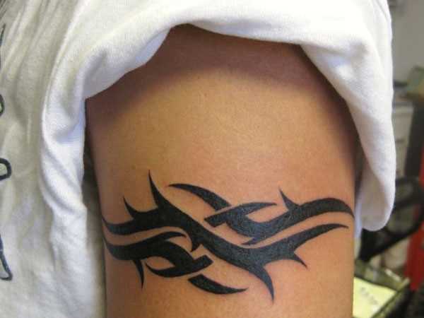 A tatuagem de padrões em estilo tribal no braço do cara