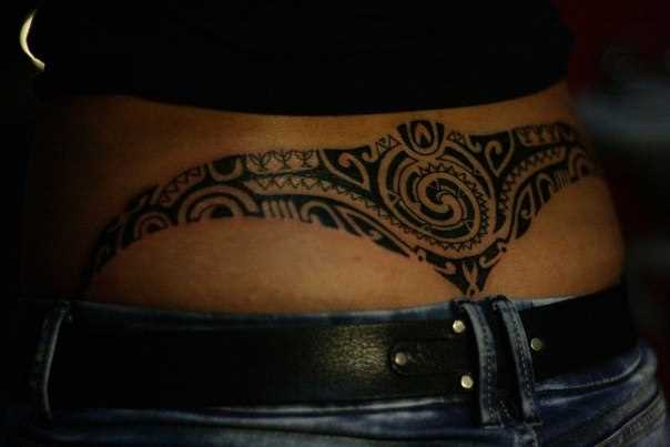A tatuagem de padrões no cóccix menina no estilo tribal