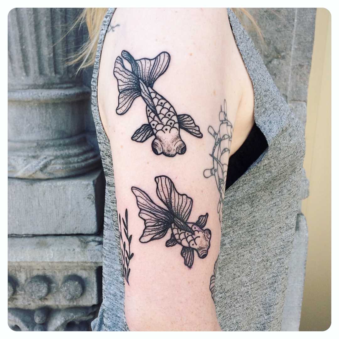 A tatuagem de peixes de ouro no ombro da menina