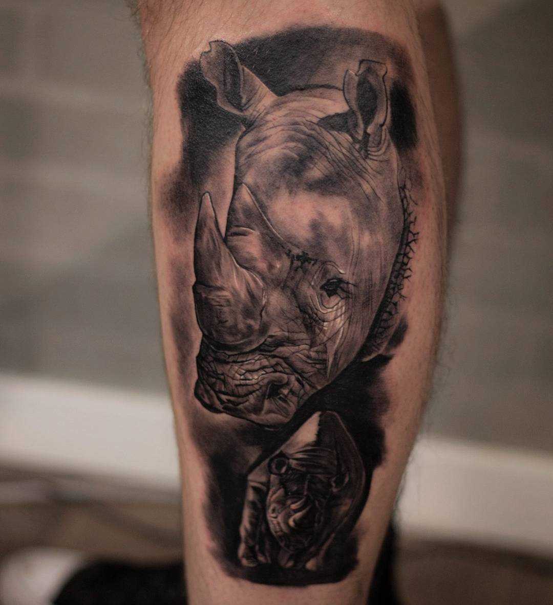 A tatuagem de rinocerontes sobre a perna de um cara