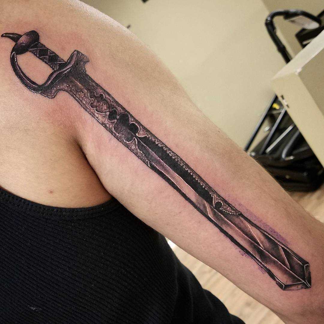 A tatuagem de uma espada no ombro do cara