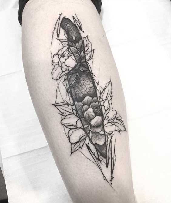 A tatuagem de uma faca com flores sobre a perna da menina