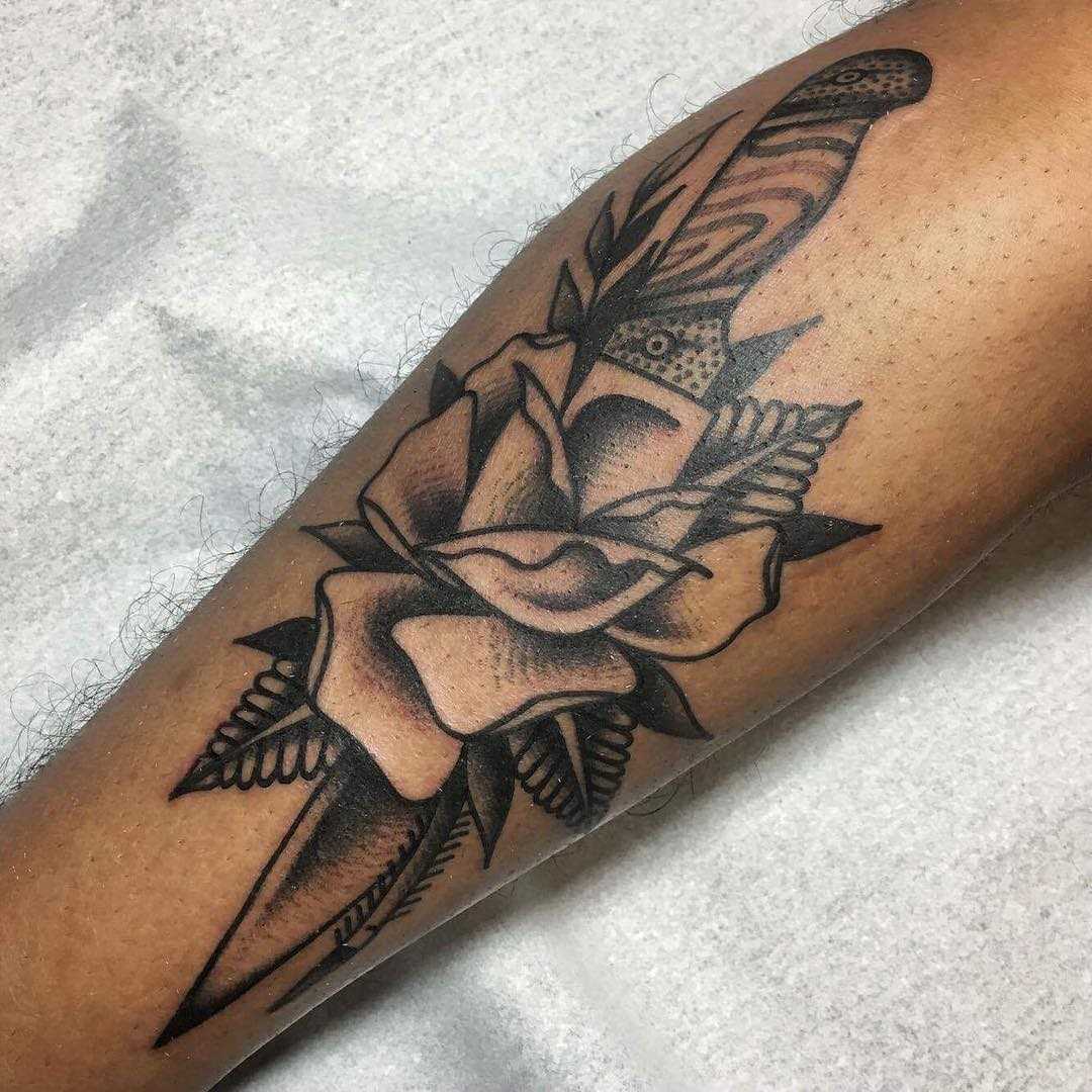 A tatuagem de uma faca com uma rosa na perna do cara