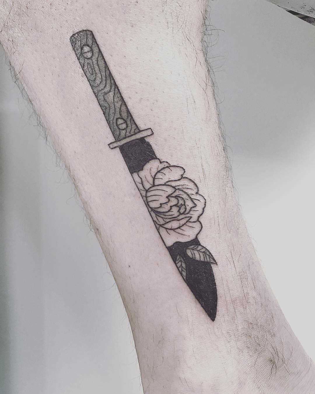 A tatuagem de uma faca com uma rosa no antebraço homens
