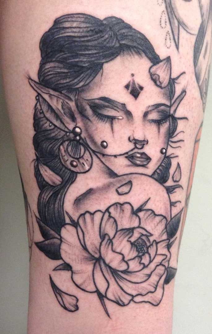 A tatuagem de uma menina elfo com uma flor no quadril da menina
