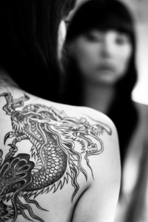A tatuagem de uma menina em uma lâmina em forma de dragão