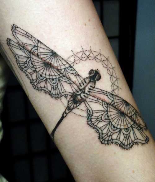 A tatuagem de uma menina no antebraço - mandala como as asas de uma libélula