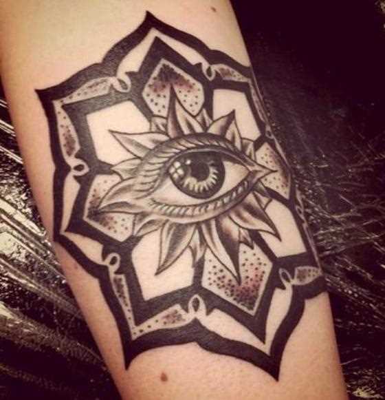A tatuagem de uma menina no antebraço - mandala e os olhos