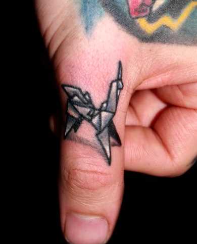 A tatuagem de uma menina no dedo - unicórnio-origami
