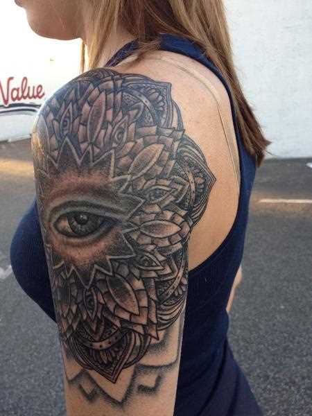 A tatuagem de uma menina no ombro - a mandala e o olho