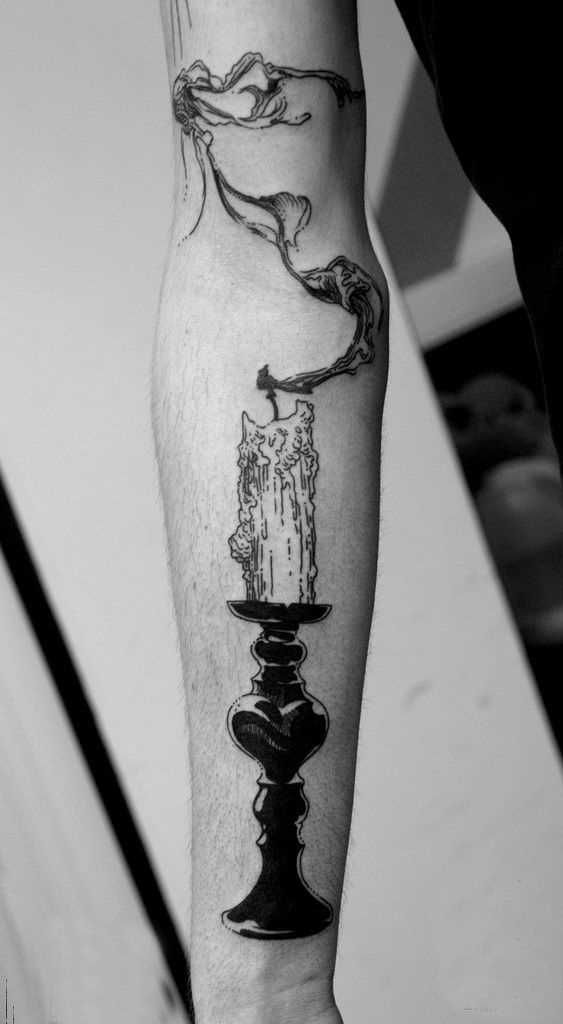 A tatuagem de uma vela na mão de um cara