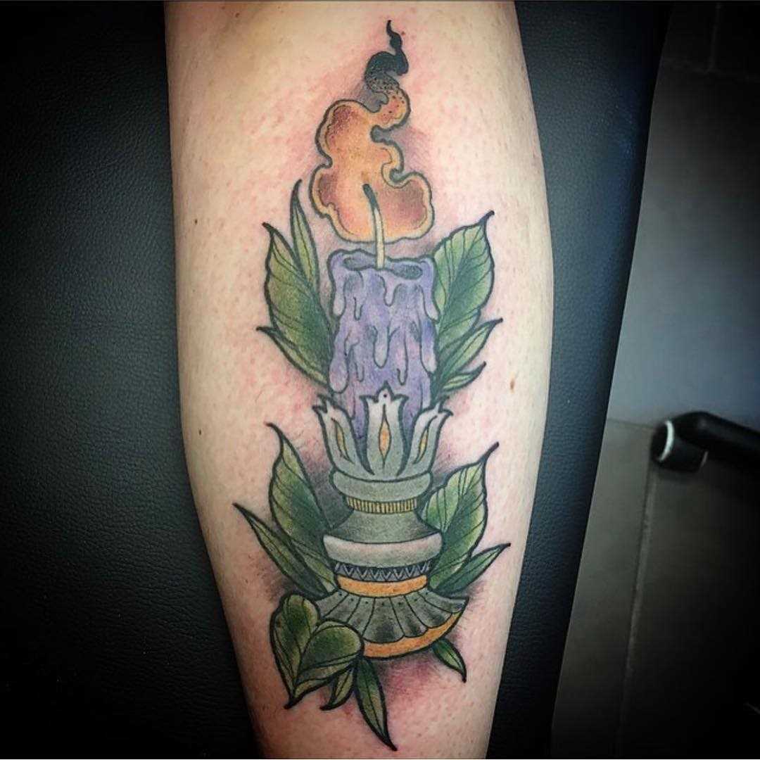 A tatuagem de uma vela sobre a perna da mulher