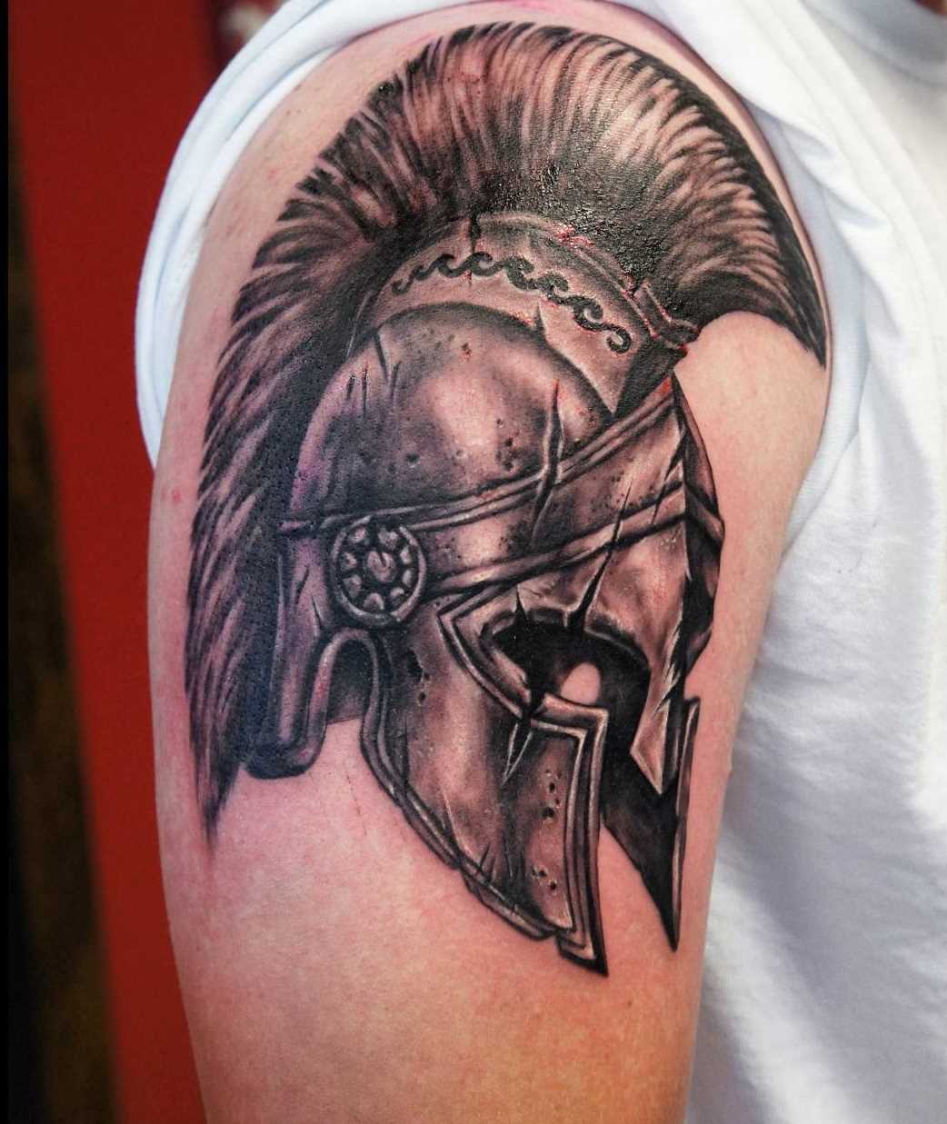 A tatuagem do capacete spartan no ombro do cara