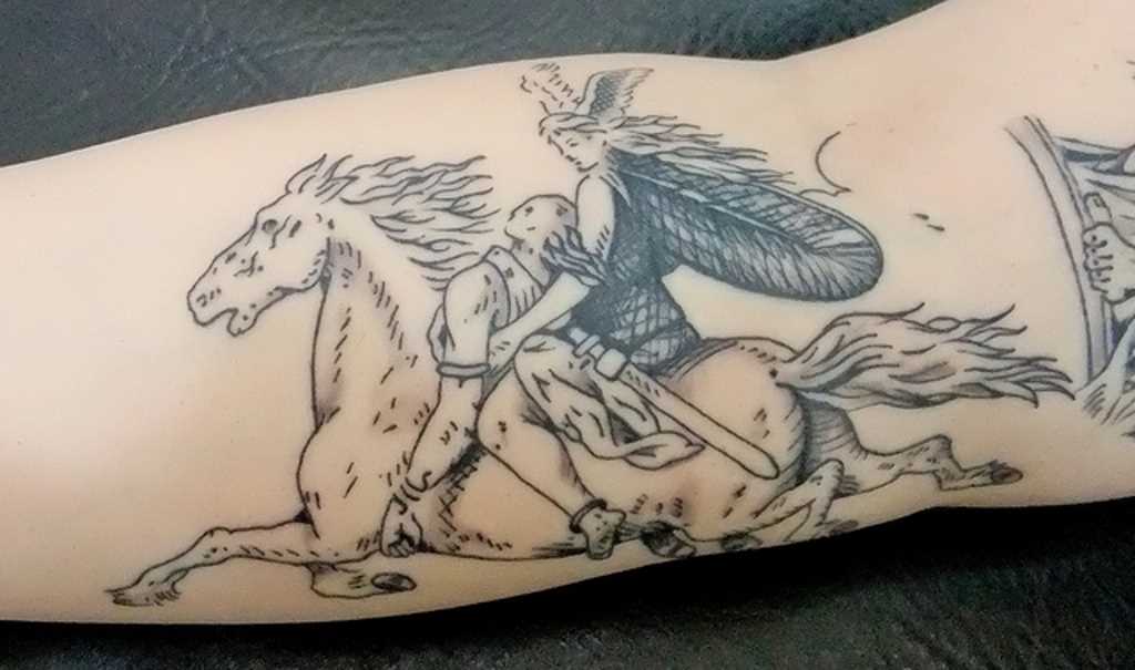 A tatuagem do cara no antebraço - Valkyrie sobre o cavalo