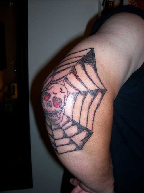 A tatuagem do cara no cotovelo em forma de teias de aranha e o crânio
