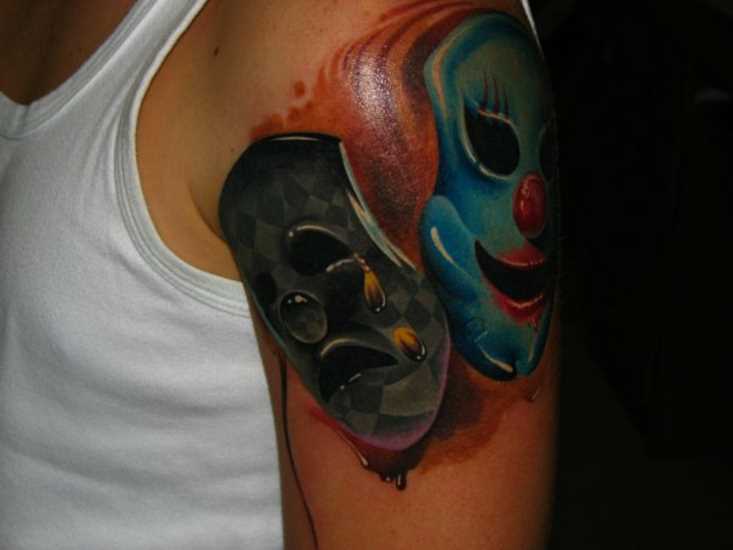 A tatuagem do cara no ombro com a imagem de máscaras