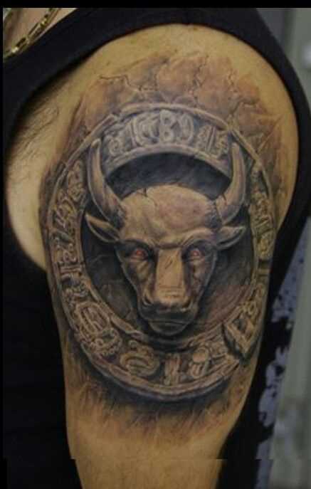 A tatuagem do cara no ombro com a imagem de um touro sobre a rocha