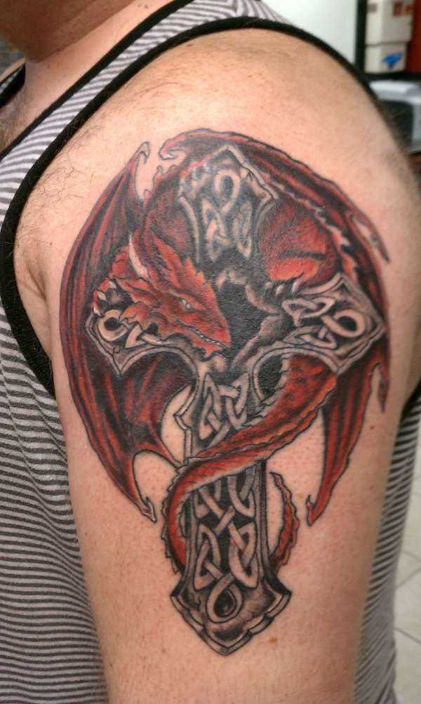 A tatuagem do cara no ombro em forma de dragão vermelho e a cruz