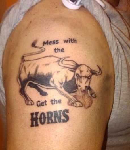 A tatuagem do cara no ombro em forma de um touro e inscrições