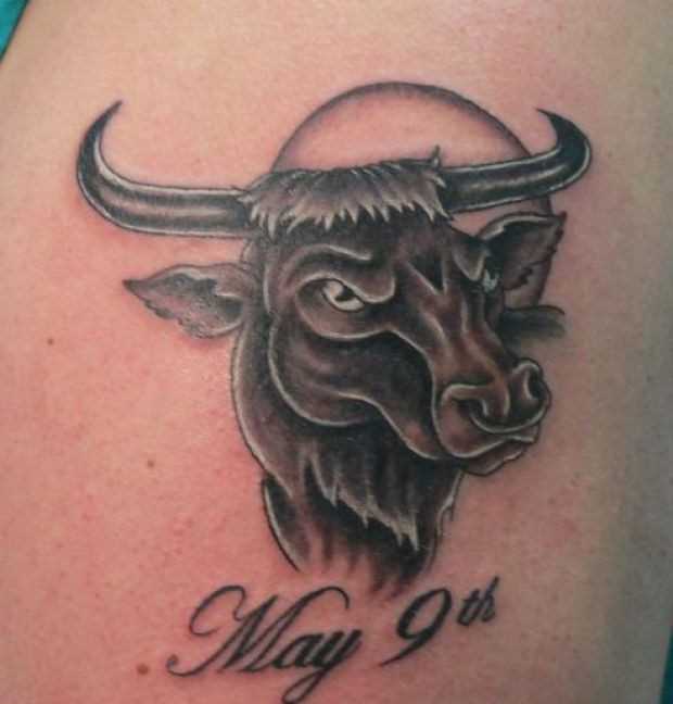 A tatuagem do cara no ombro em forma de uma cabeça de touro e inscrições