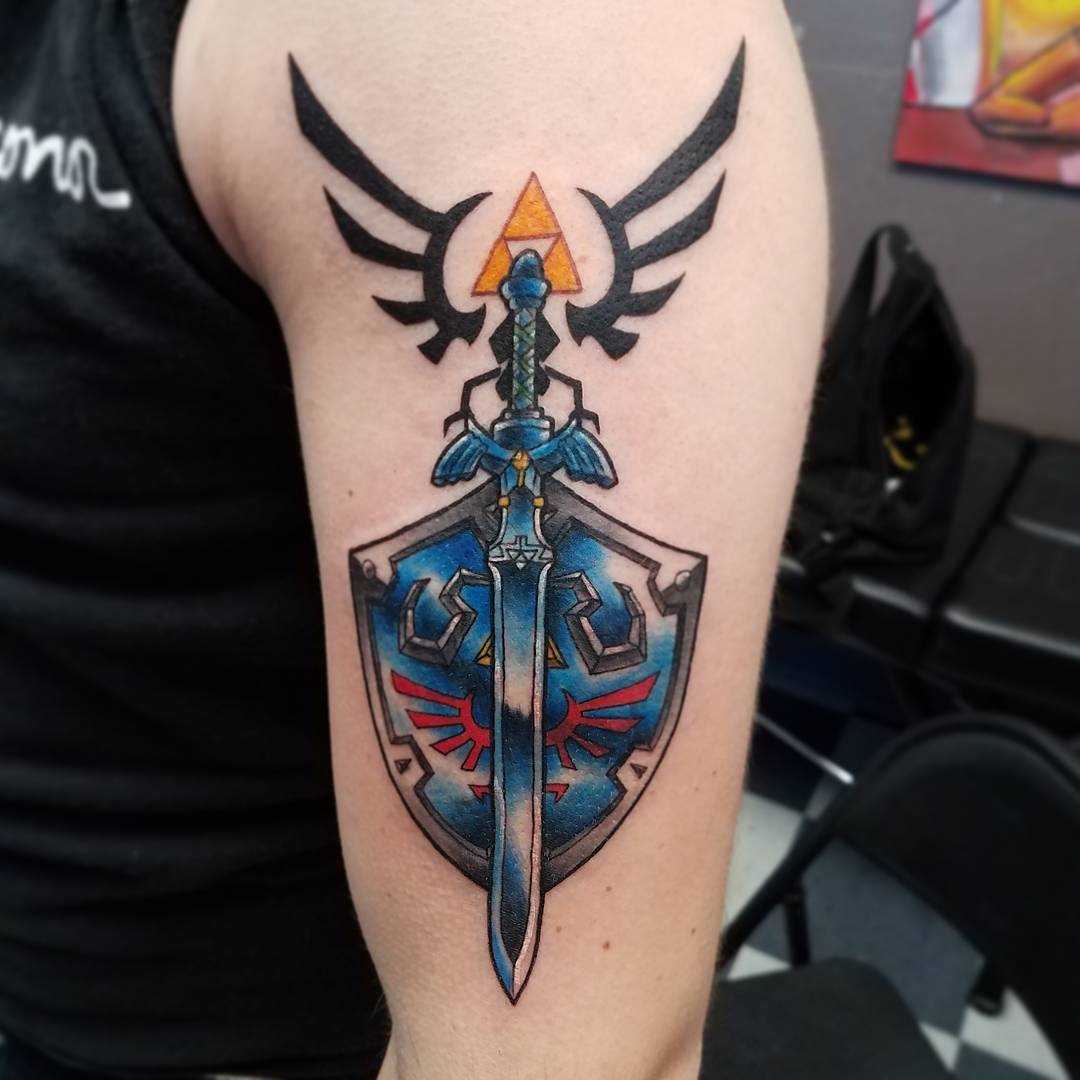A tatuagem do escudo com a espada no ombro do homem