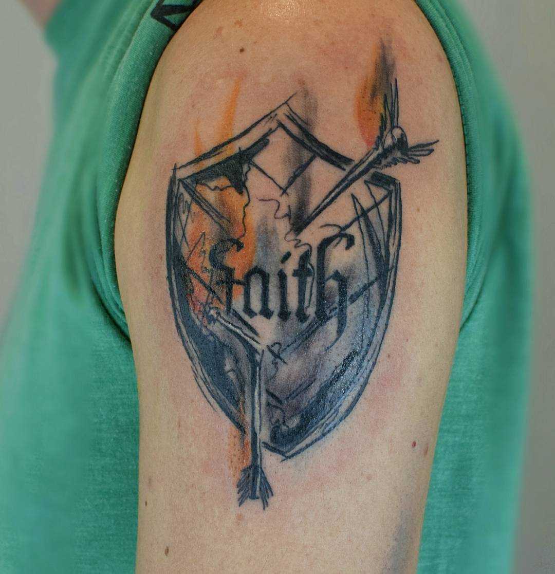 A tatuagem do escudo com flechas no ombro do cara