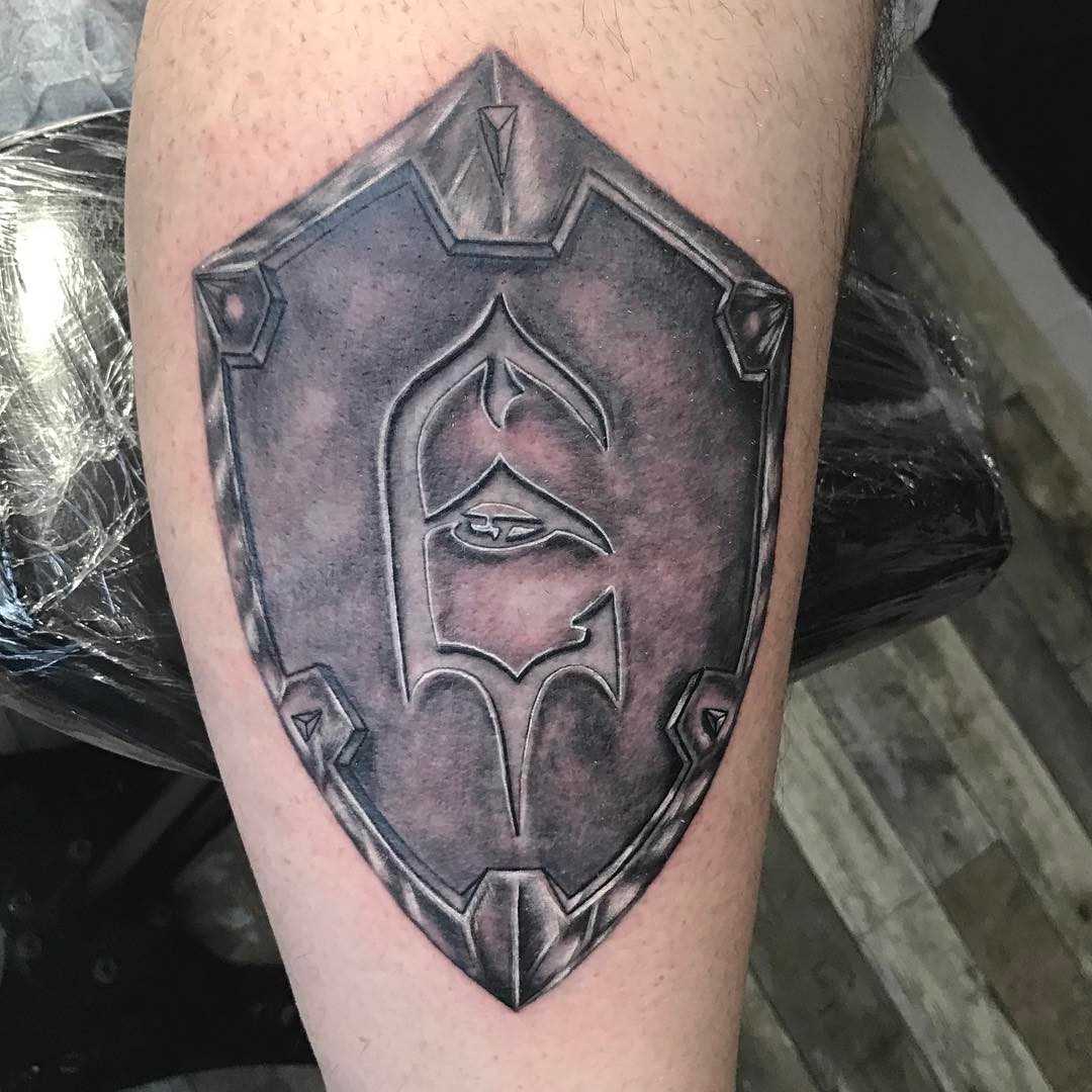 A tatuagem do escudo sobre a perna de um cara