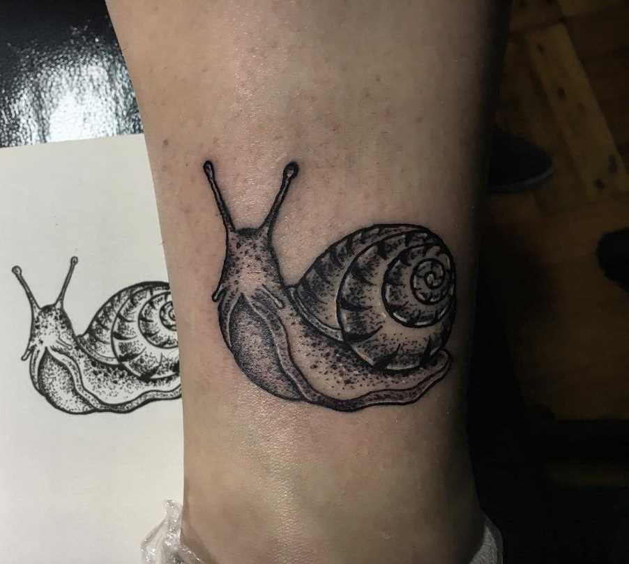 A tatuagem é um caracol sobre a perna da mulher