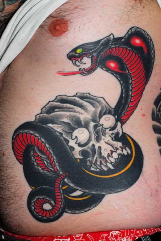 A tatuagem em forma de serpentes e caveiras na lateral do cara