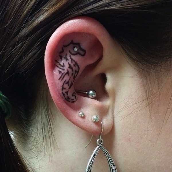 A tatuagem estilo tribal no ouvido da menina - cavalo marinho