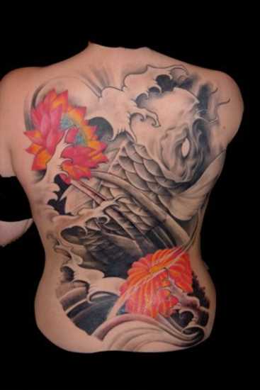 A tatuagem nas costas de uma menina - carpa e lótus