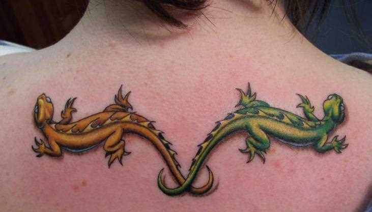 A tatuagem nas costas de uma menina como dois lagartos