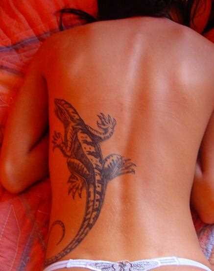 A tatuagem nas costas de uma menina em forma de lagarto