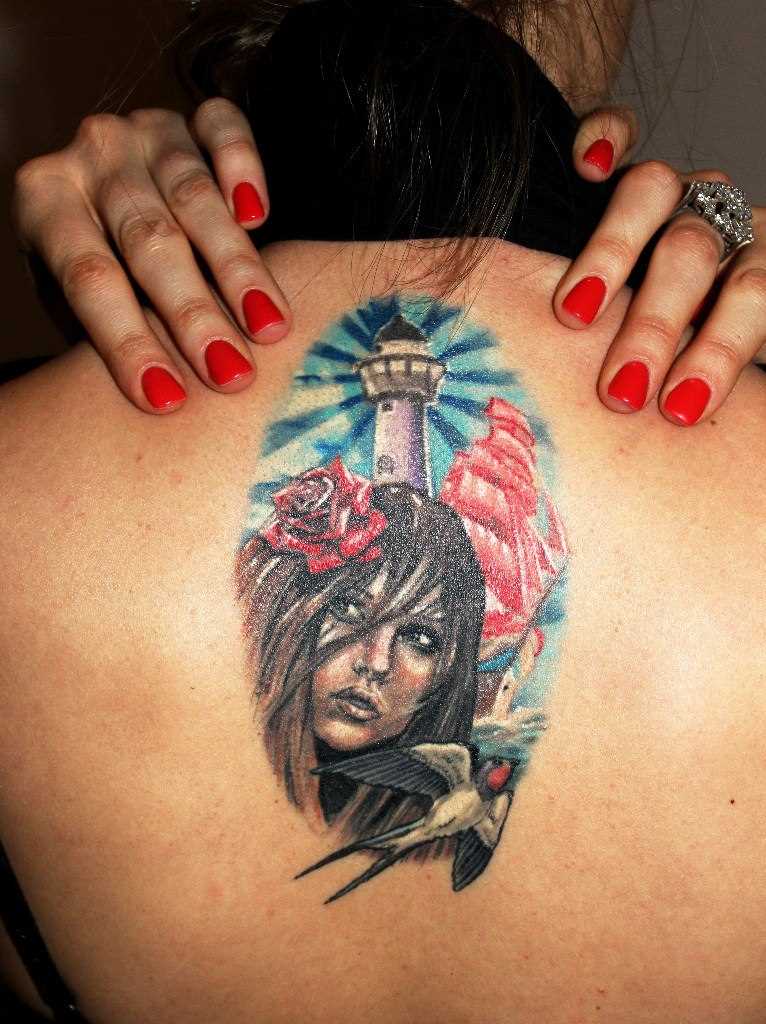 A tatuagem nas costas de uma menina - farol, de ofício, a menina e a andorinha