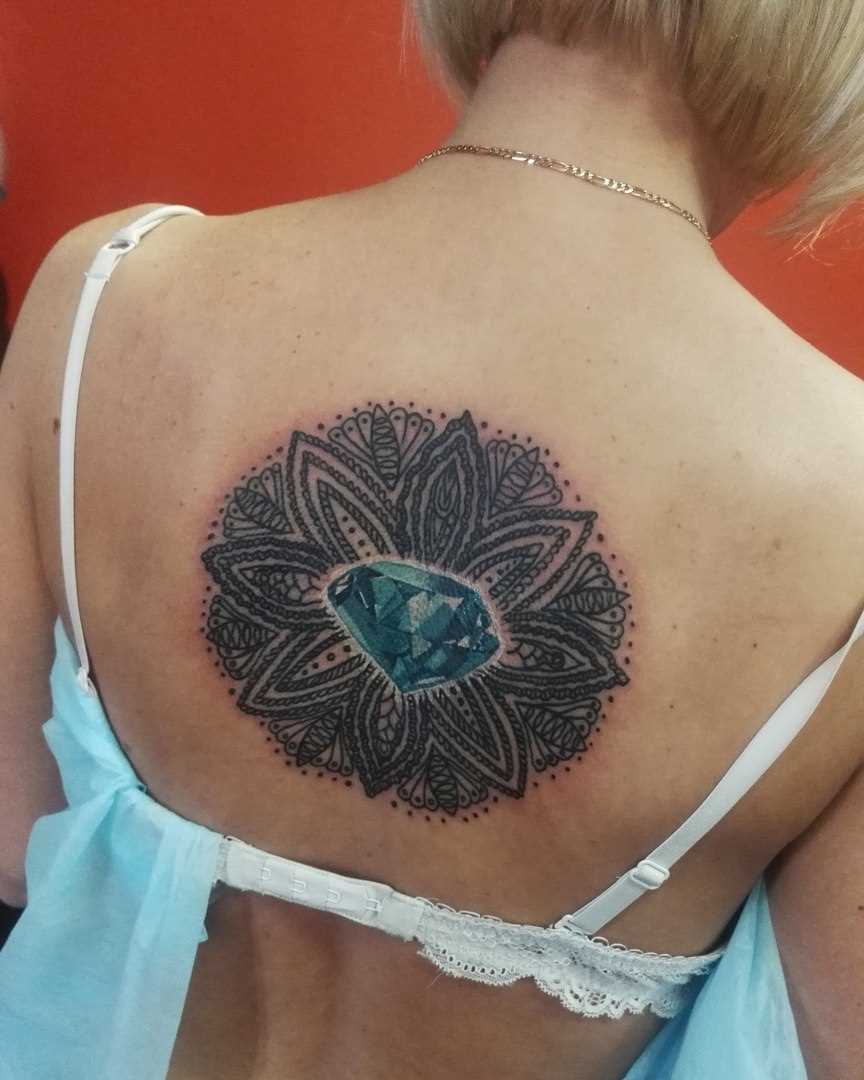 A tatuagem nas costas de uma menina - mandala e diamante