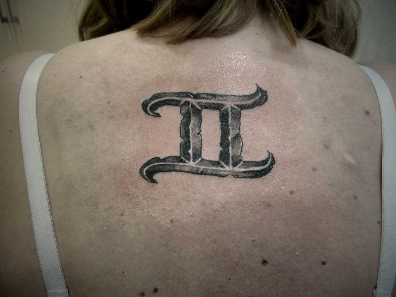 A tatuagem nas costas de uma menina - signo de Gêmeos
