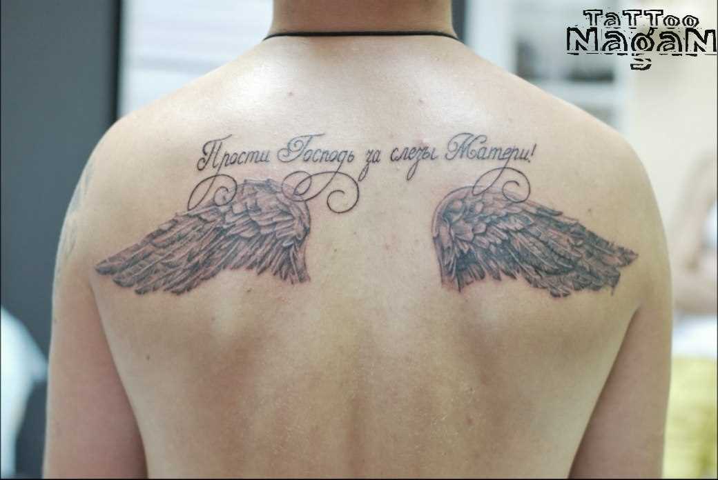 A tatuagem nas costas do cara - asas e inscrição