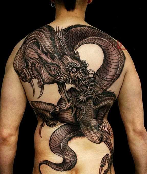 A tatuagem nas costas do cara em forma de um grande dragão