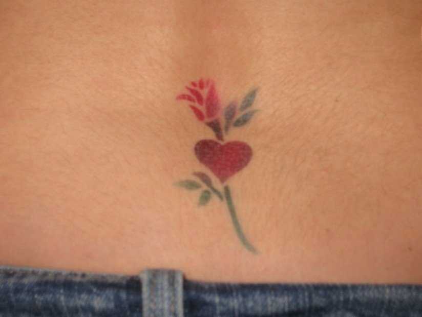 A tatuagem no cóccix menina de coração de rosa